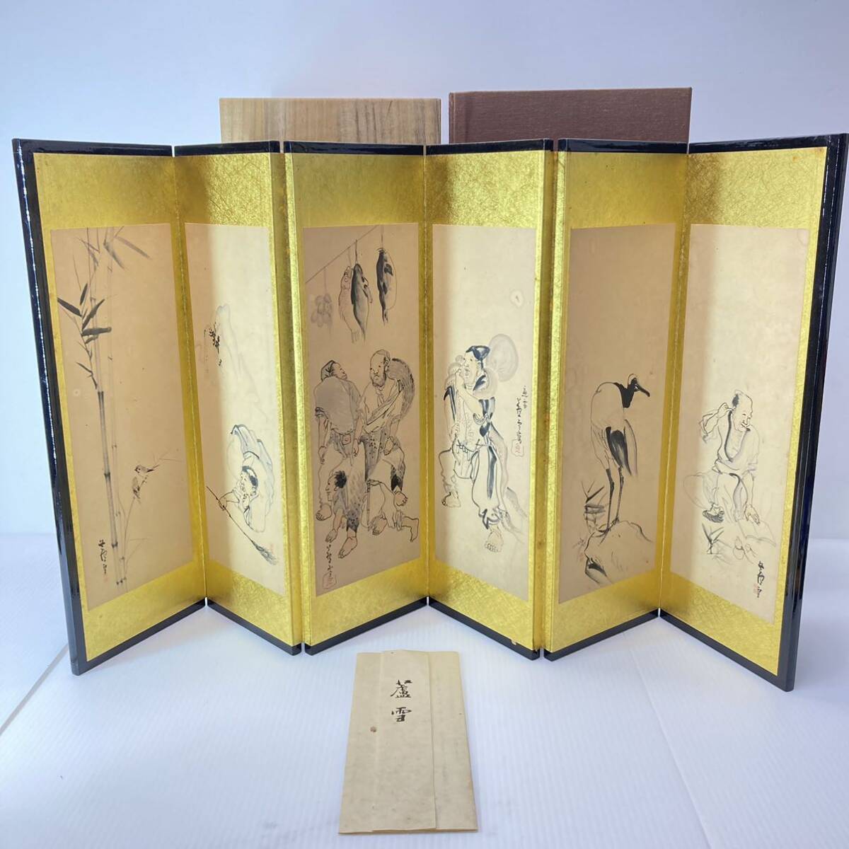 Traditional Japanese folding screen artwork displayed alongside a collector's boxed PlayStation 3 console in a styled living room setting